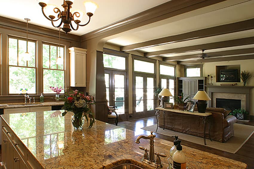 Open-plan living area with kitchen island, granite countertops, fireplace, and multiple French doors.