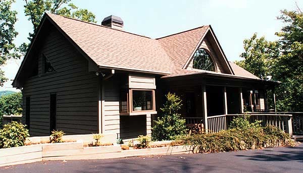 House plan exterior with dark siding, gable roof, a large arched window, and a covered porch with railings.