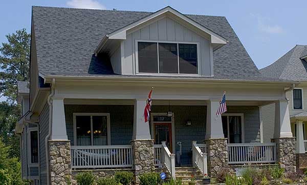 House plan exterior: Two-story home with a covered front porch, stone base pillars, dormer, and gable rooflines.