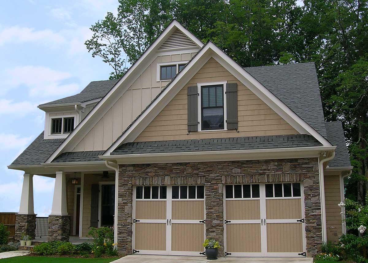 House plan exterior: Two-story Modern Farmhouse with stone accents, two garage doors, gable dormer, and covered porch.
