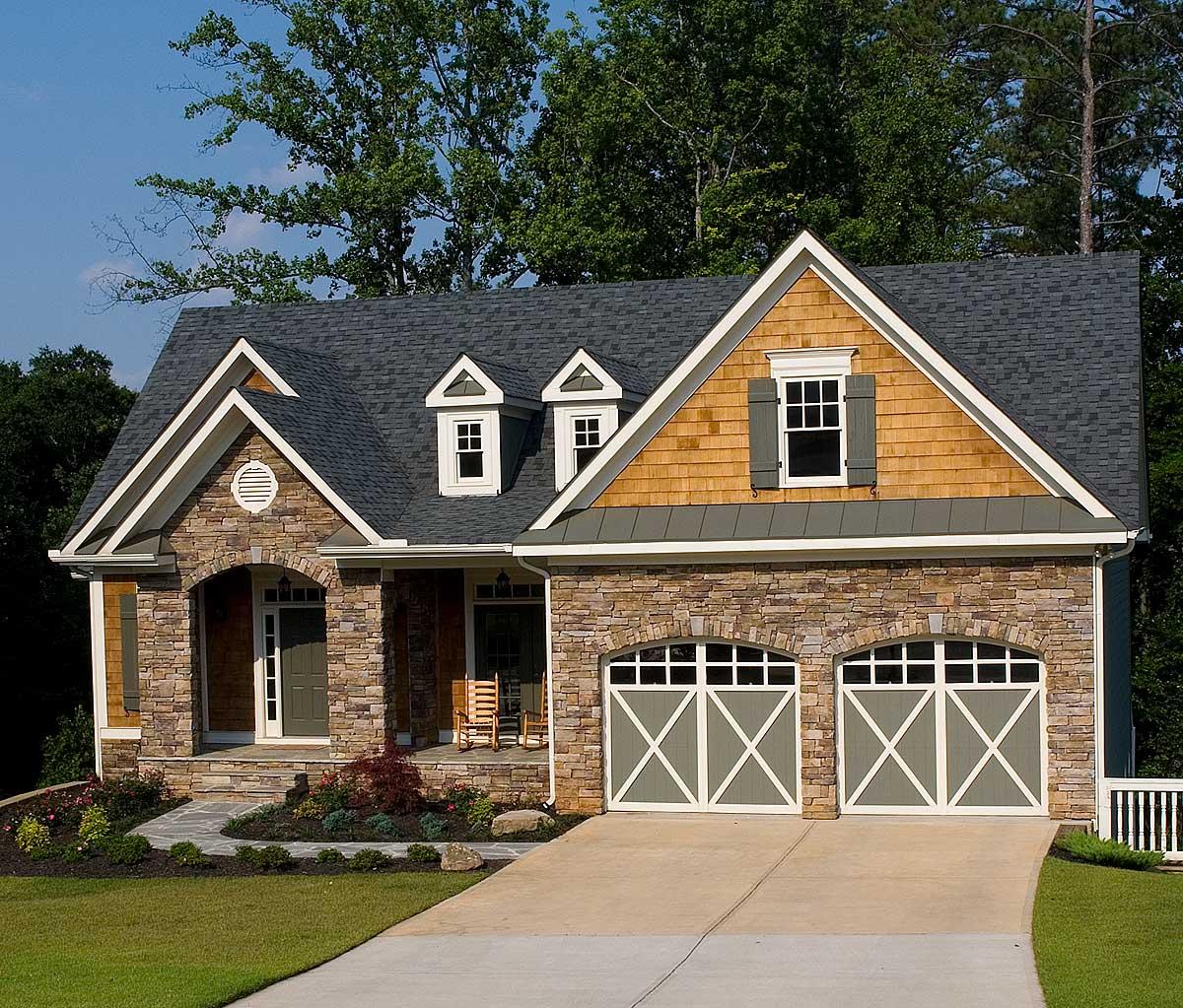 House plan exterior: Two-story home with stone and cedar siding, dormers, and a double garage.
