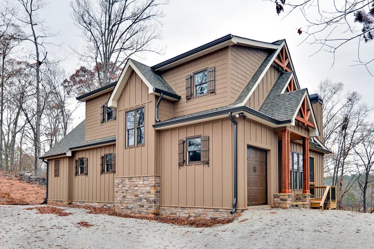 House plan exterior featuring Craftsman architectural style. Two-story home with gables, stone accents, wood porch columns, and a garage.