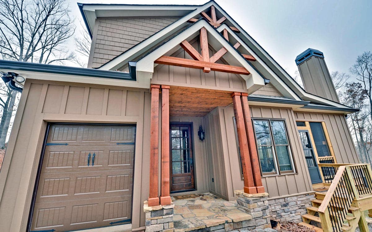 Craftsman style house plan exterior with side garage, stone foundation, wooden porch columns, and exposed rafter tails.