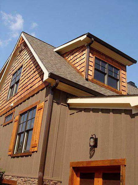 House plan exterior showing a multi-story design with shingle-clad gables, wood shutters, and a dormer.