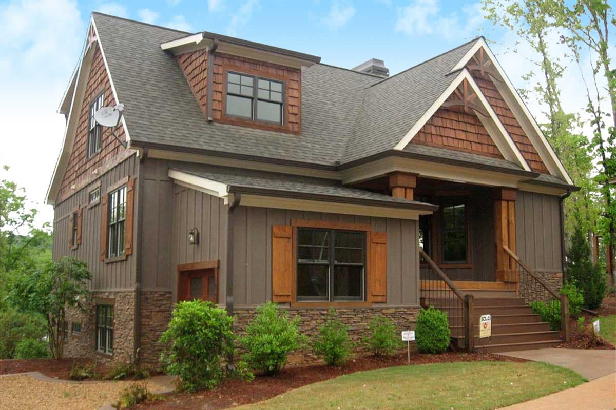 House plan exterior of a two-story Craftsman-style home with board-and-batten siding, stone accents, dormer, and covered porch.