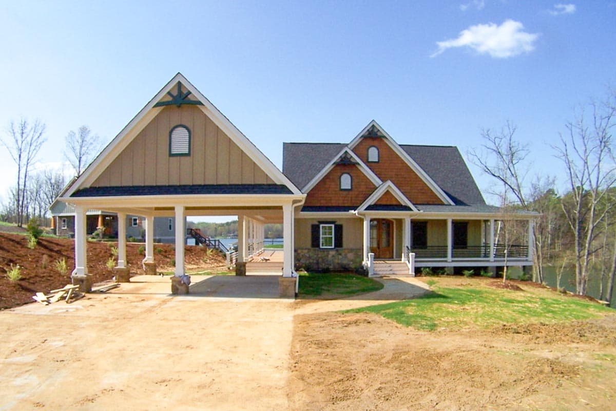 House plan exterior with attached carport, gable dormers, and wraparound porch.