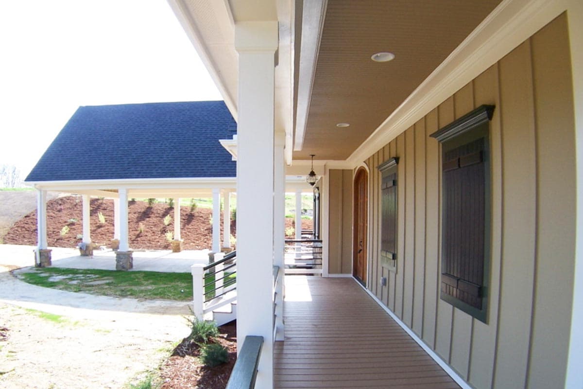 House plan exterior showing a wide covered porch with Doric columns, paneled siding, and two tall windows with shutters.