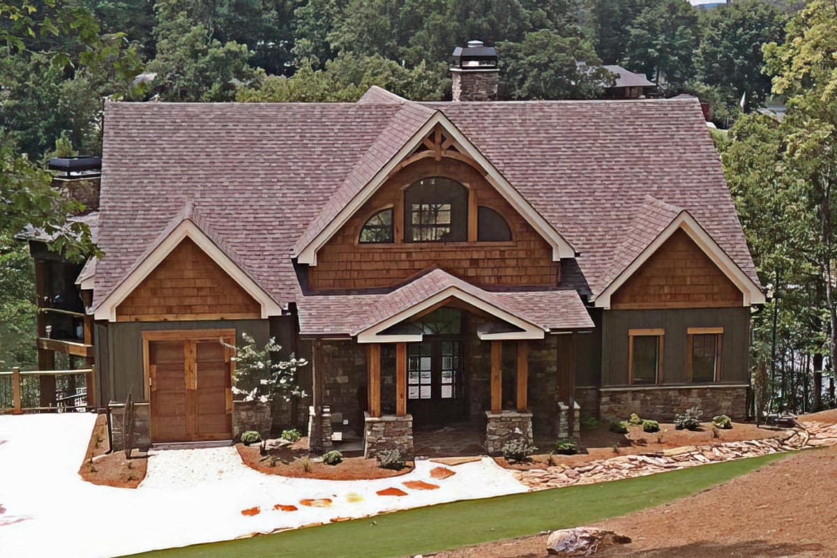 House plan exterior: Lodge style, two-story home with stone accents, wood shingle siding, prominent gables, and a covered entry.
