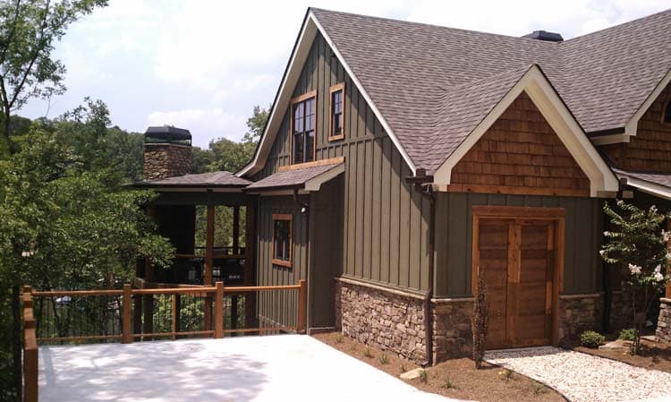 House plan exterior: A two-story Modern Farmhouse with stone base, vertical siding, dormers, and a stone chimney.