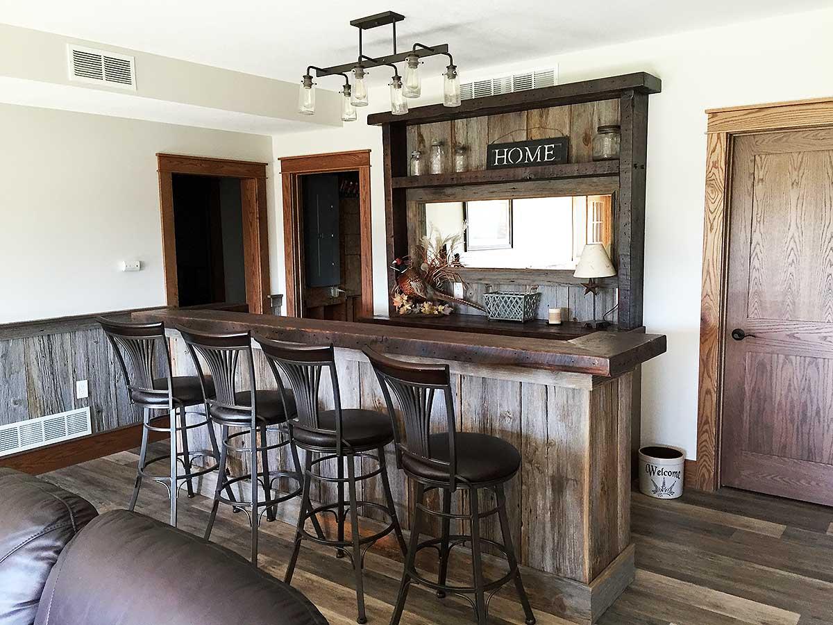 Interior bar area with rustic wood paneling, a granite countertop, and four metal bar stools.