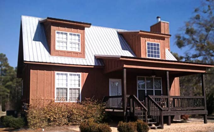 House plan exterior featuring a two-story wooden cabin with metal roof, dormers, covered porch, and stone chimney.