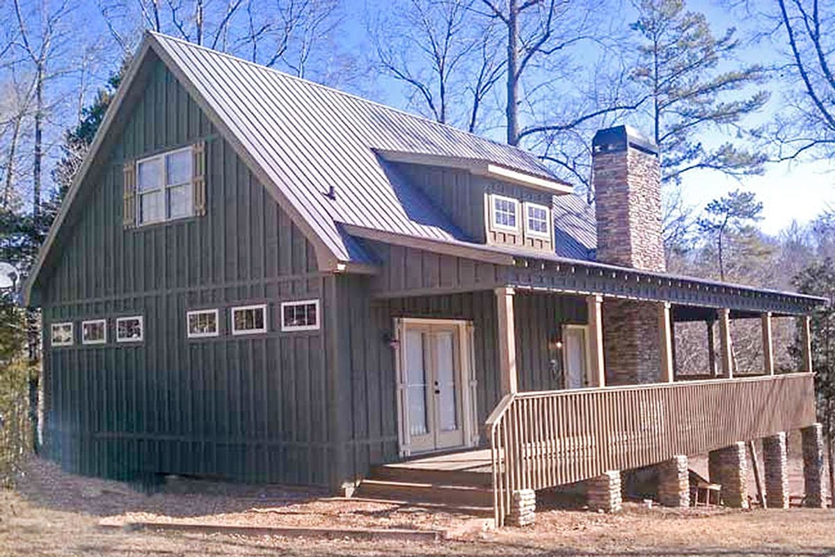 House plan exterior: A two-story Modern Farmhouse with a metal roof, stone chimney, and wraparound porch.