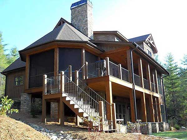 House plan exterior view of a multi-story home with a screened porch, stone chimney, and wraparound deck.