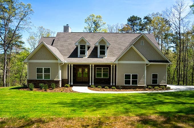 House plan exterior. Ranch style with a single story, front porch with columns, gables, dormers, and a prominent roofline.