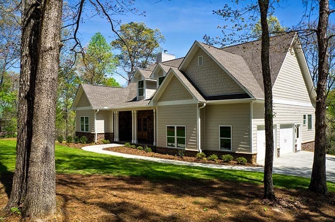House plan exterior: Ranch-style home with a covered front porch, dormers, and a side-entry garage.