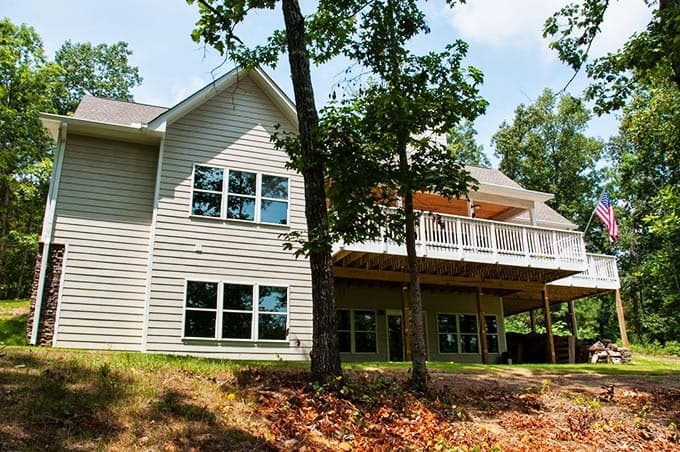 House plan exterior of a two-story home with vinyl siding, stone accent, deck, and gabled roof.