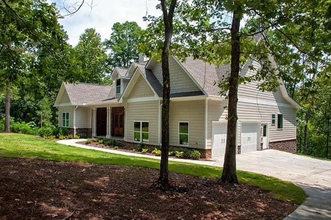House plan exterior: Ranch style, 1.5 stories, with a covered front porch, dormers, and a side-entry two-car garage.