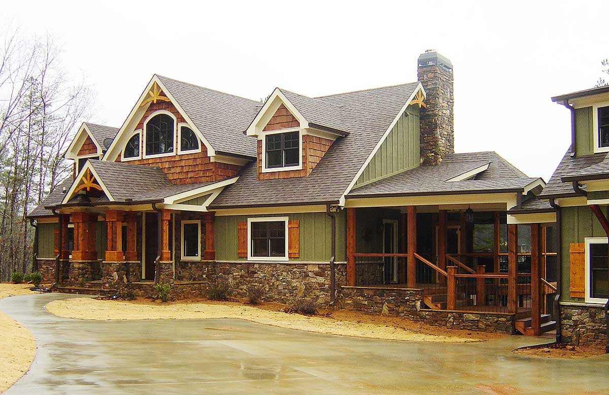 House plan exterior: Two-story Craftsman style with stone foundation, deep covered porch, multiple gables, and dormer windows.