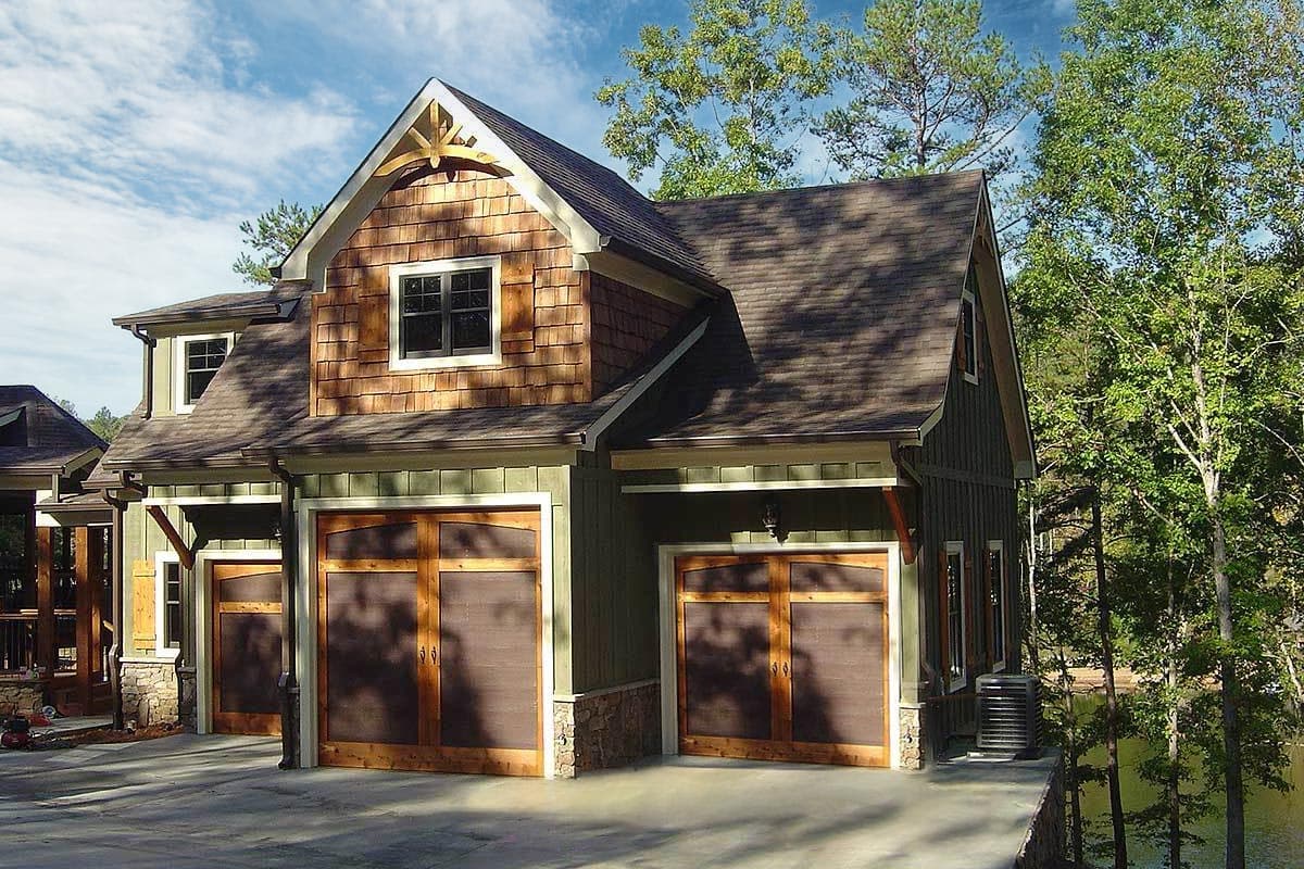 House plan exterior: Craftsman style with two garage bays, cedar shake siding, and prominent gables with decorative rafter tails.