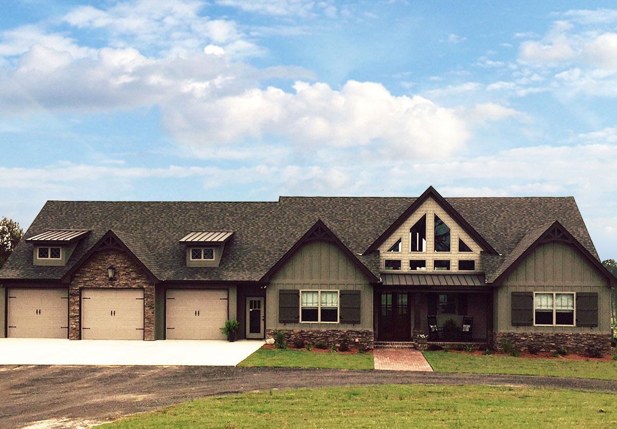 House plan exterior. Ranch style with multiple gables, stone accents, dormers, and covered front porch. Three-car garage on the left side.