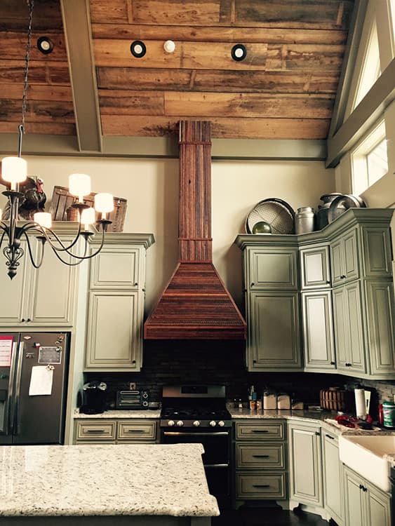 Kitchen with vaulted wood plank ceiling, exposed beams, and a custom wood range hood over stove.