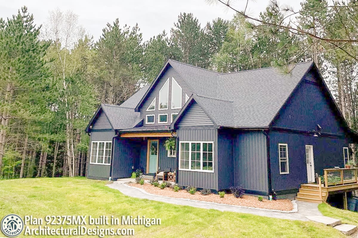 House plan exterior with a dark gray vertical board and batten siding, gabled roof, and multiple windows.