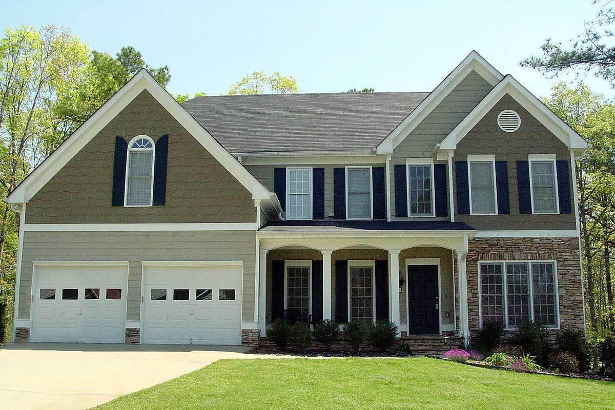 Two-story house plan exterior with two-car garage, arched gable dormer, stone accents, and covered entryway.