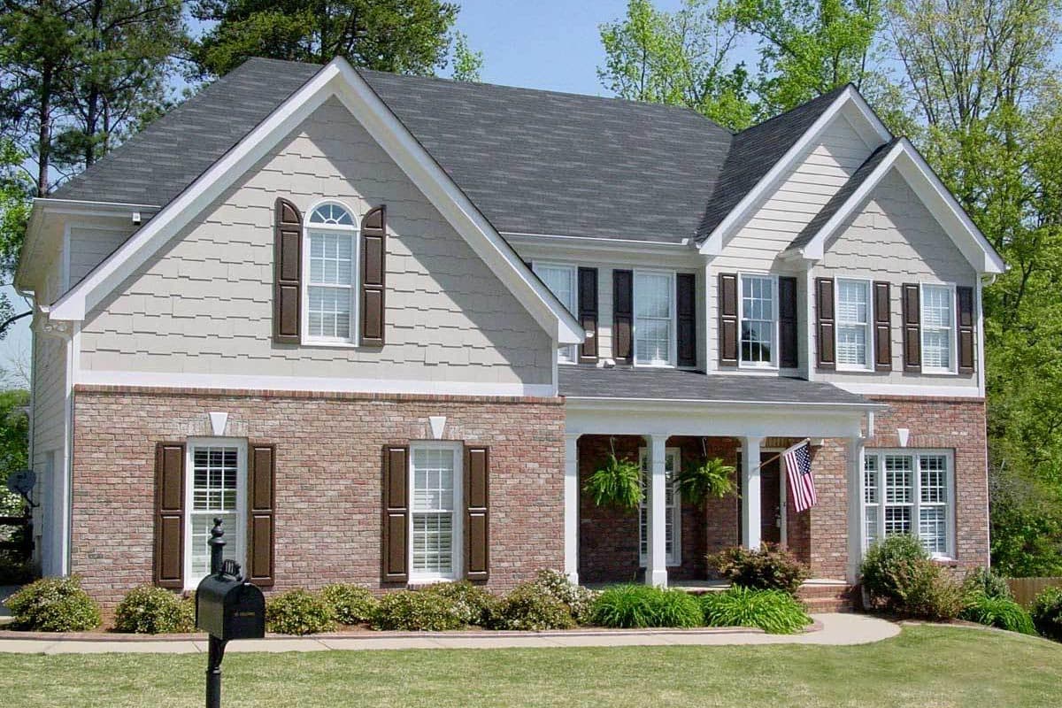 House plan exterior: Two-story home with brick and shake siding, gable dormers, and a covered front porch.