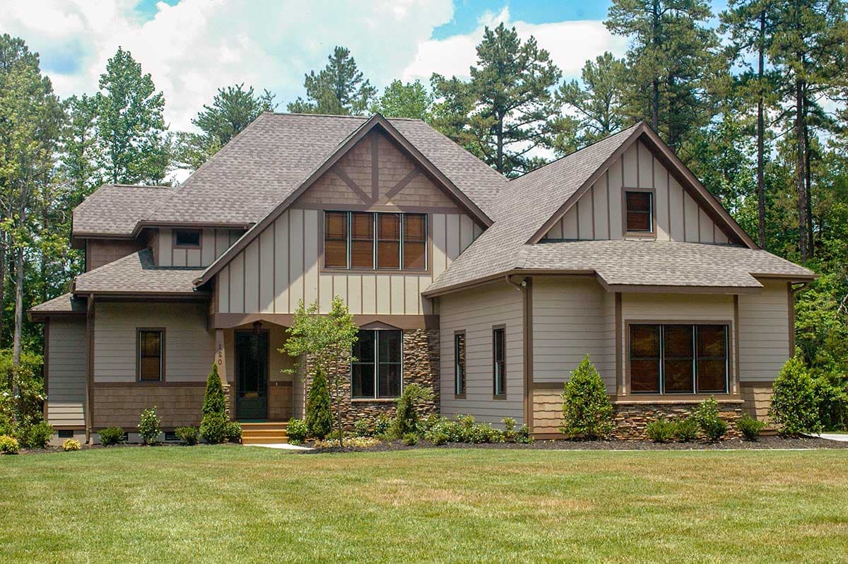 House plan exterior with Tudor-style gables, stacked stone accents, and a covered entry porch.