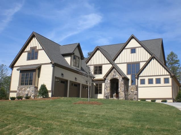 House plan exterior with multiple gables, stone arch entry, and three-car garage.