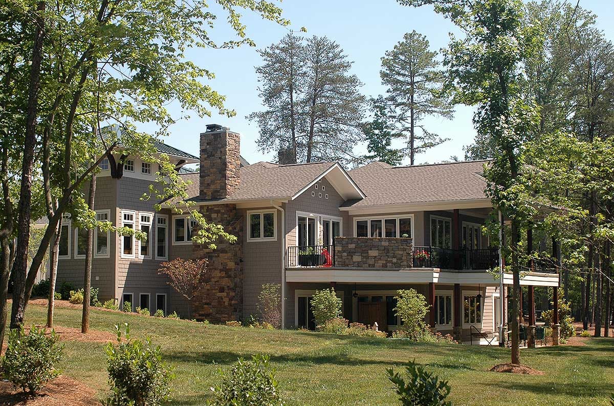 House plan exterior, multi-story home with stone chimney, gabled roof, dormers, and covered balconies.