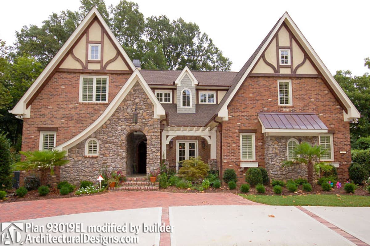 House plan exterior features stone arched entryway, brick facade, and multiple gables with half-timbering. Two stories visible.