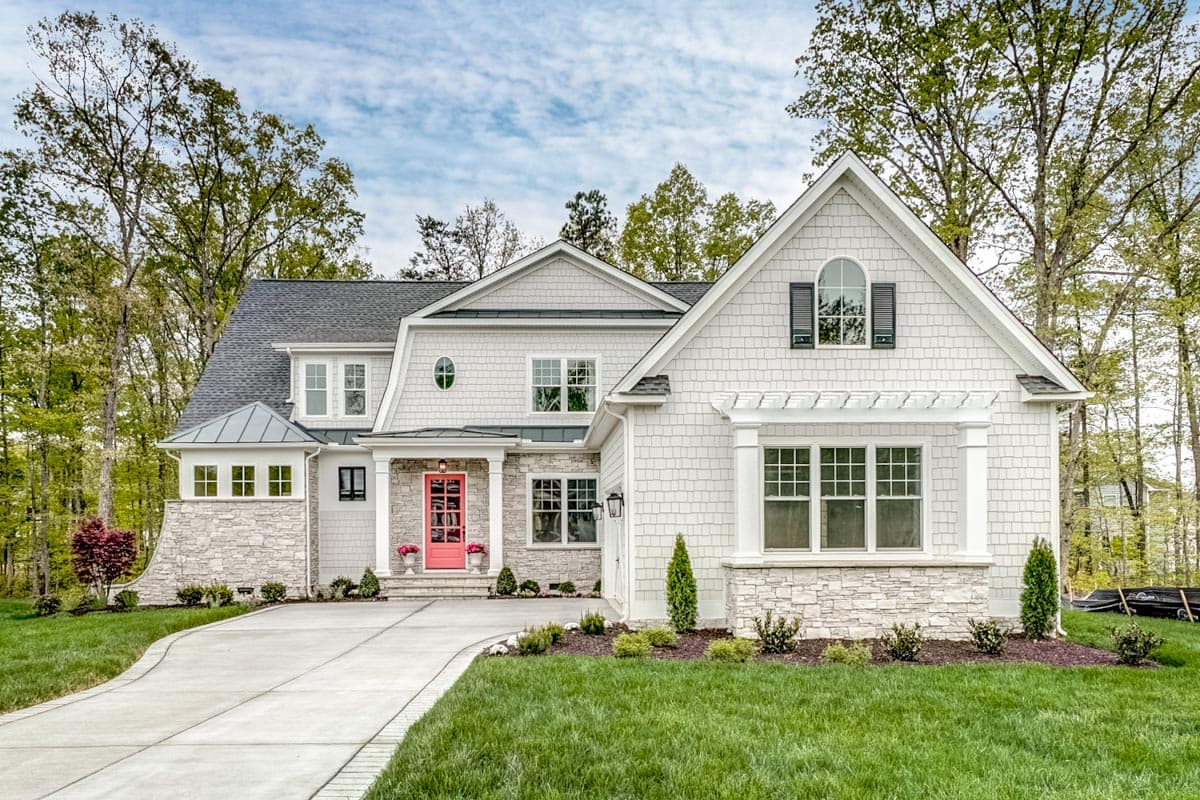 House plan exterior featuring a two-story design with a front porch, gables, and a mix of shingle and stone siding.