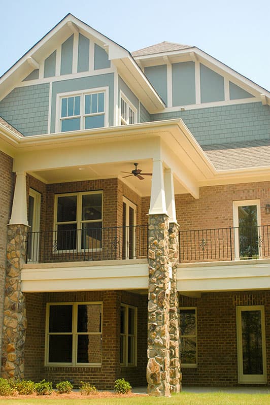 Craftsman house plan exterior with stone pillars, covered balcony, gables, and multi-story dormers.