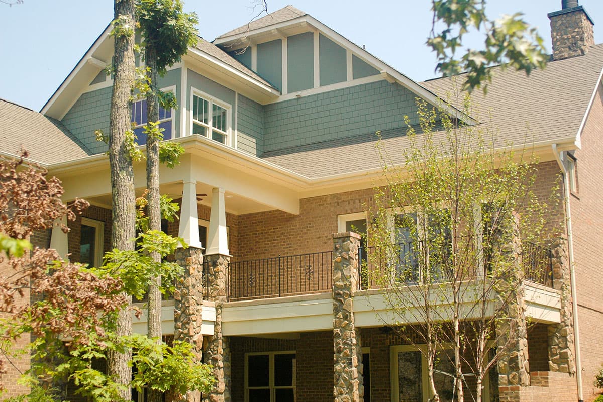 House plan exterior with brick and shake siding, a covered porch with stone columns, and multiple gables.
