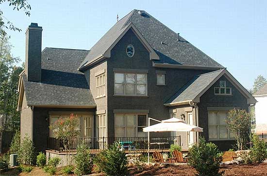 House plan exterior: Two-story home with prominent chimney, multiple gables, second-story dormer, and deck.