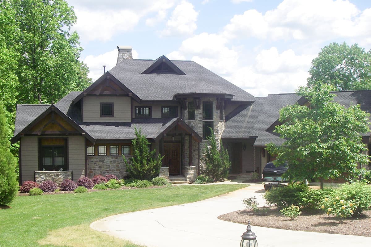 House plan exterior with stone and wood accents, multiple gables, a dormer, and a prominent covered entryway.