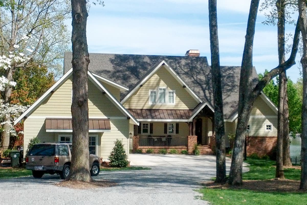 House plan exterior featuring a hip roof, gabled dormers, and a covered front porch with brick columns.