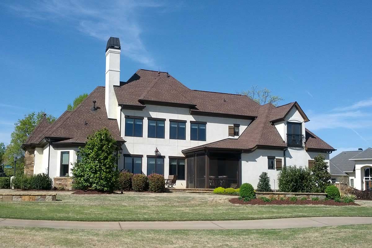 Exterior view of a two-story house plan with a prominent chimney, a screened porch, and multiple gables.