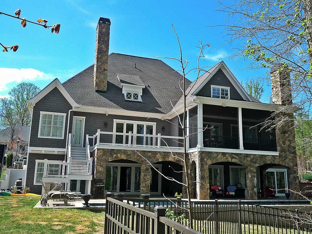 House plan exterior with stone foundation, multiple gables, dormers, a screened porch, and stone chimney.
