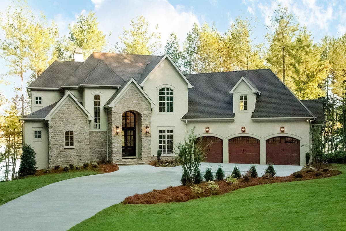 House plan exterior, two stories, stone accents, arched entry, and a three-car garage with arched doors.