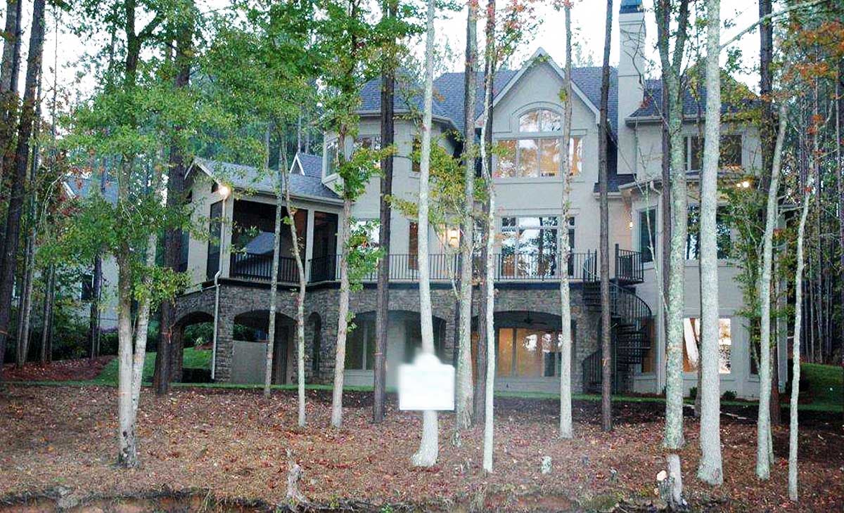 House plan exterior: multi-story home with screened porch, arched stone foundation, and spiral staircase.