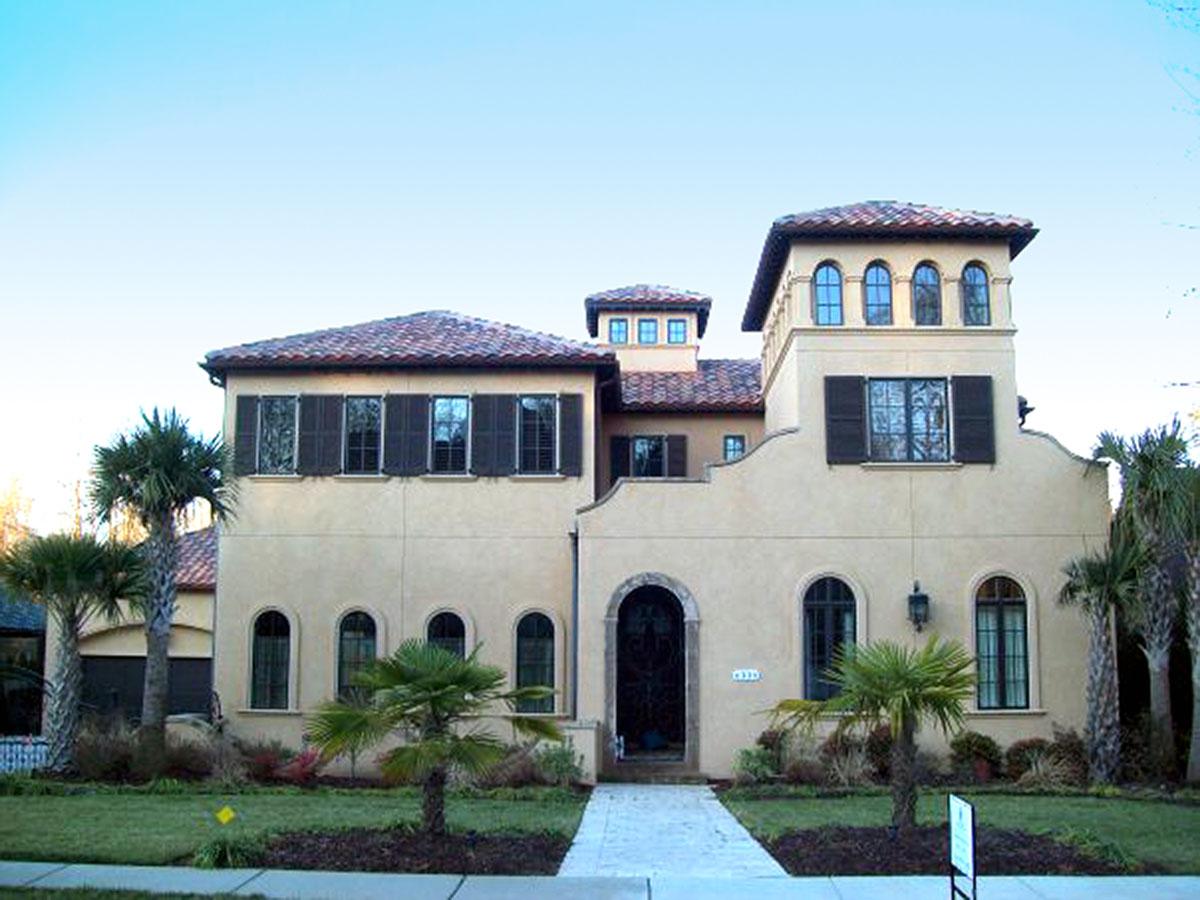 House plan exterior: Mediterranean style, two stories, stucco finish, arched windows, tile roof, prominent tower.