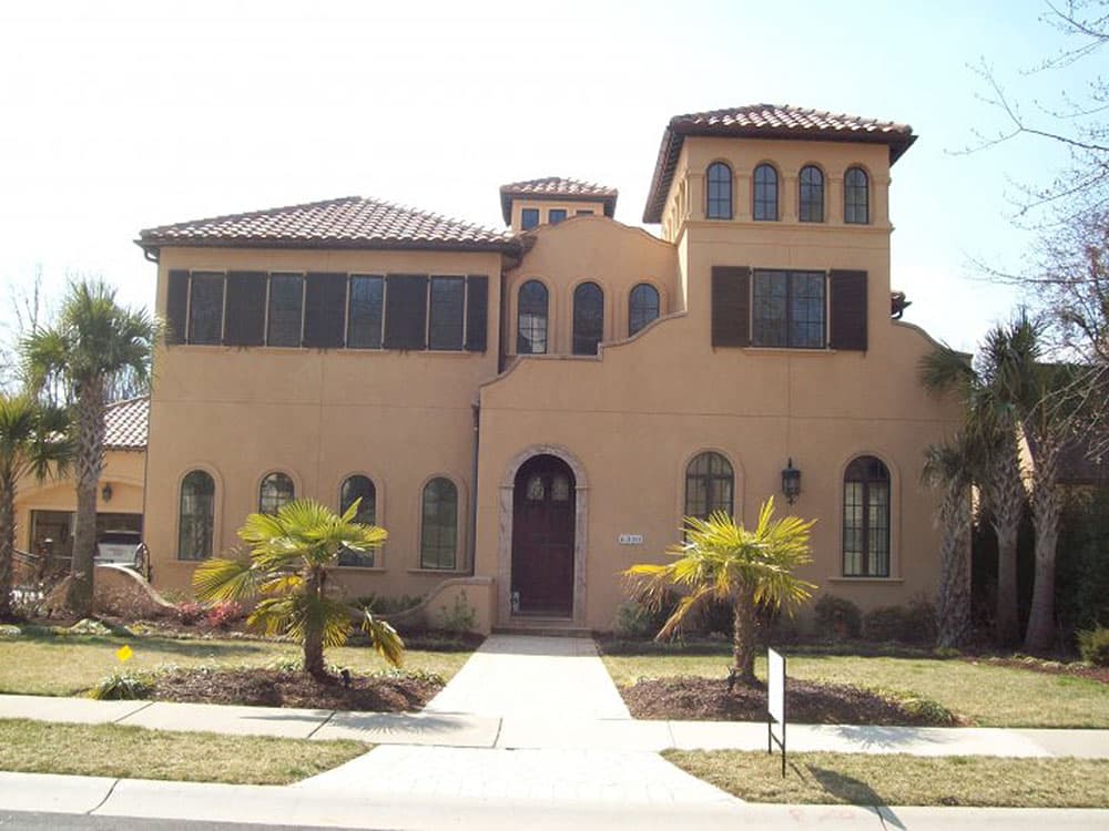 Mediterranean style house plan exterior with stucco walls, arched windows, tile roof, and a prominent tower.