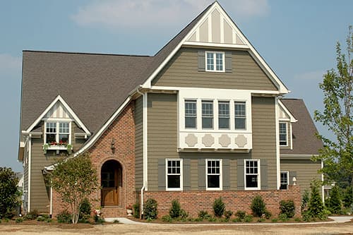 House plan exterior featuring multi-story gables, brick accents, arched entryway, and dormer windows.