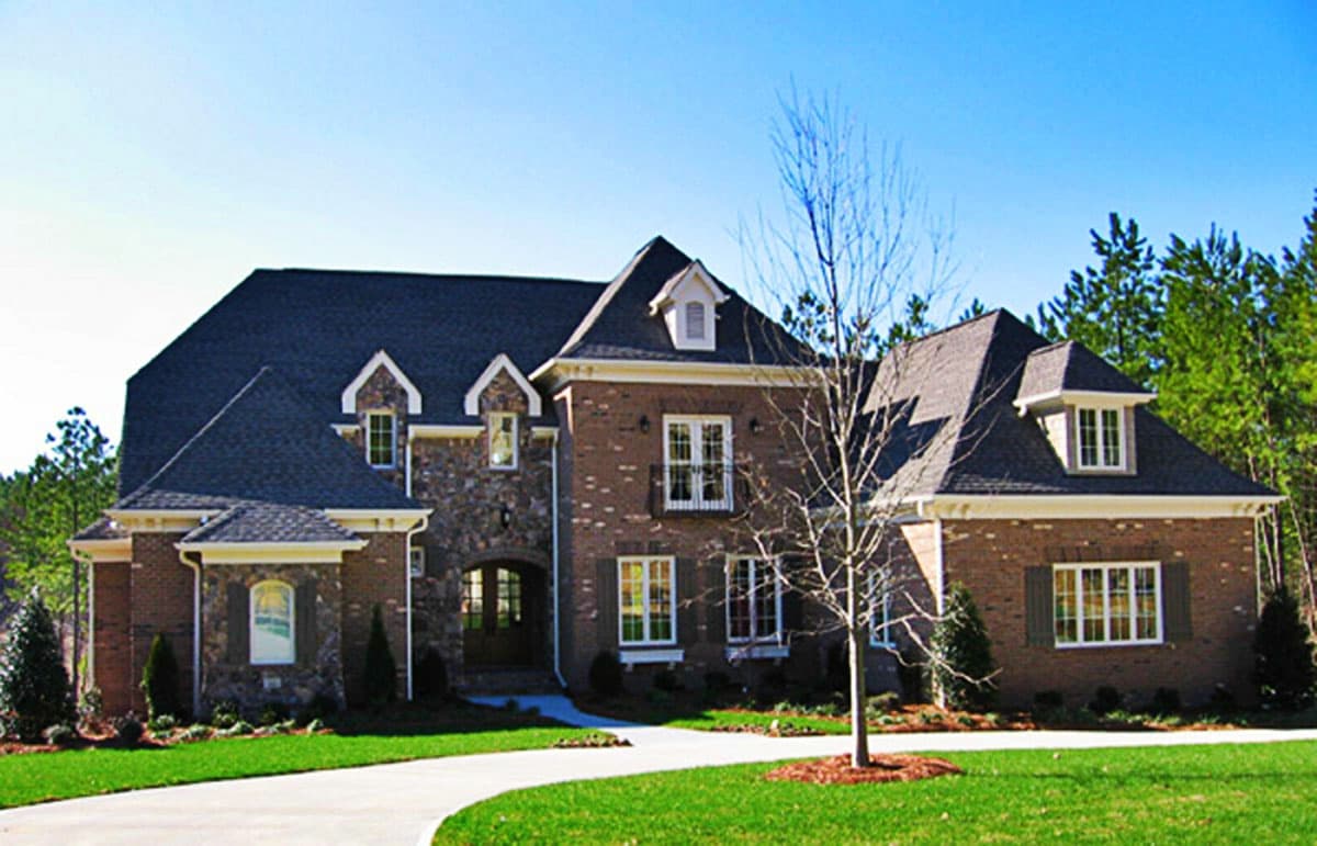 House plan exterior with two stories, brick and stone facade, dormers, multiple gables, and a prominent roofline.