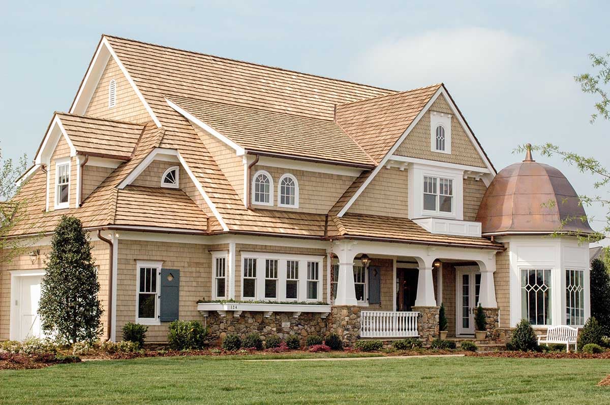House plan exterior with shingle siding, multiple gables, dormers, arched windows, a covered porch, and a copper domed turret.