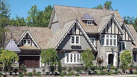 House plan exterior of a Tudor-style home with prominent gables, stone accents, decorative half-timbering, and a dormer.