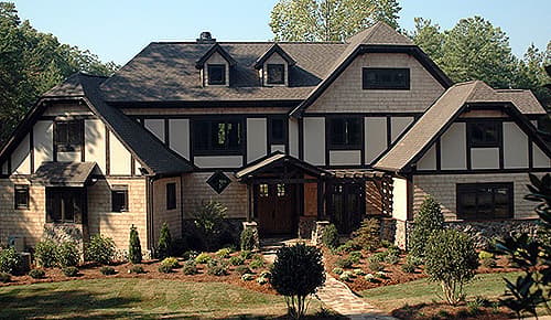 Tudor style house plan exterior with prominent gables, stone foundation, and shingle siding.