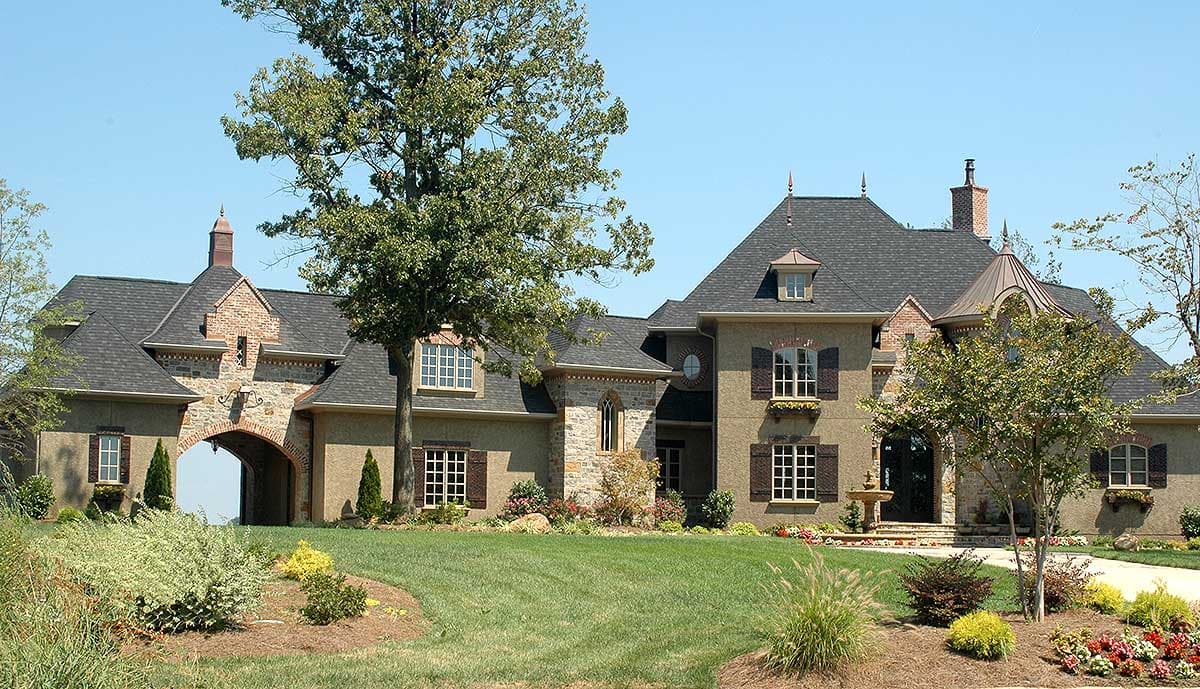 House plan exterior shows a large, multi-story home with stone accents, arched entryway, dormers, and a steeply pitched roof.